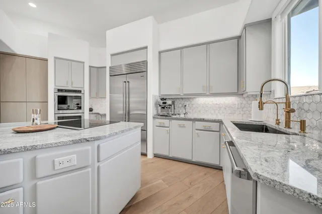 a living room with stainless steel appliances furniture a rug and a kitchen view