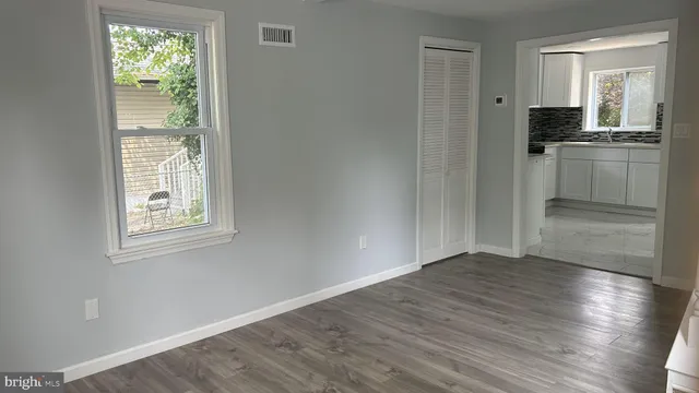 an empty room with wooden floor cabinet and windows