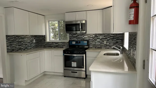 a kitchen with white cabinets and black appliances
