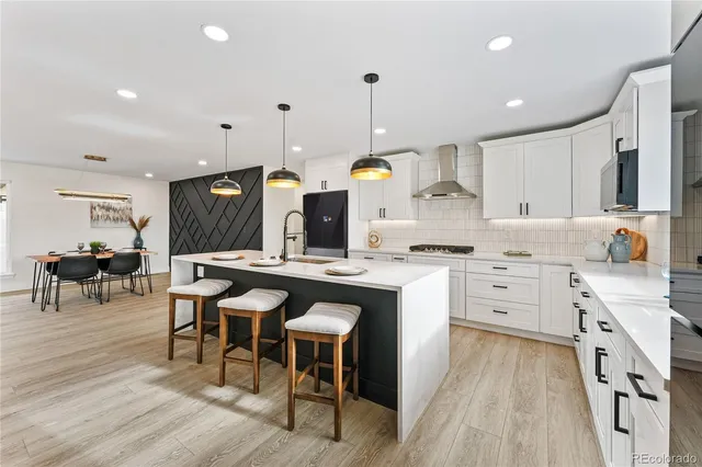 a kitchen with stainless steel appliances kitchen island granite countertop a table chairs sink and cabinets