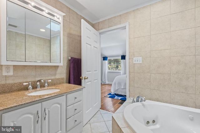 a bathroom with a granite countertop tub sink and mirror
