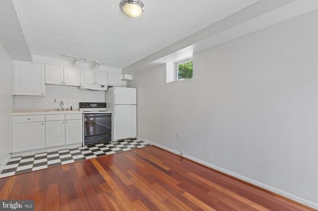 a kitchen with wooden floors and white walls