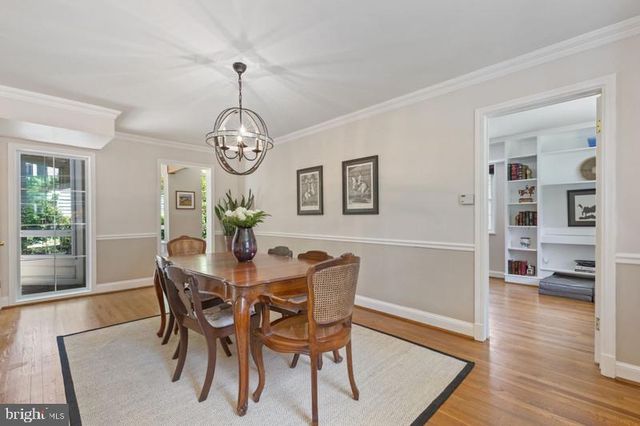 a dining room with wooden floor a chandelier a wooden table and chairs