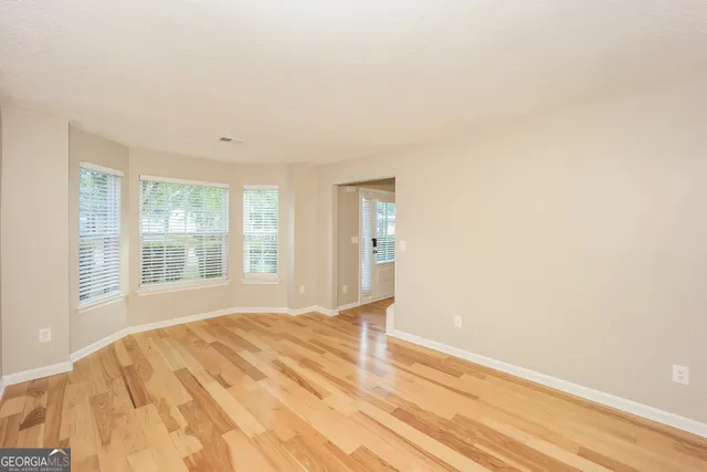 a view of an empty room with wooden floor and a window