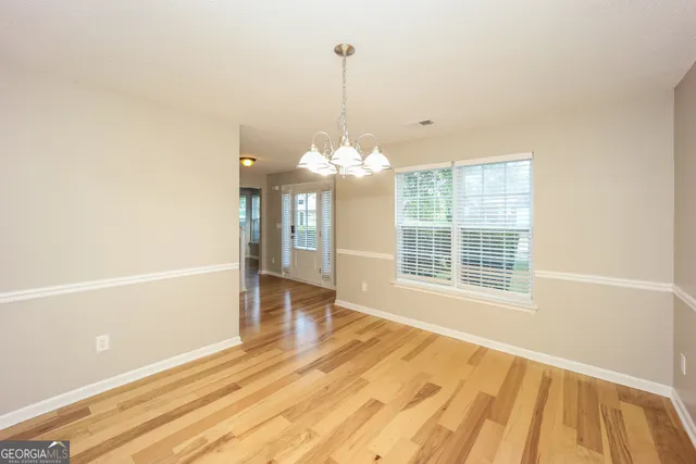 a view of a room with wooden floor chandeliers and kitchen view
