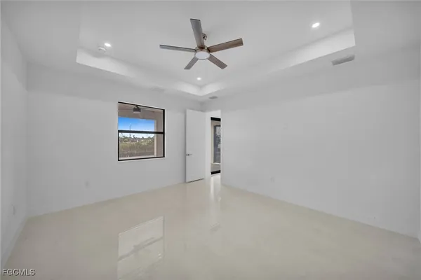 an empty room with ceiling fan and windows