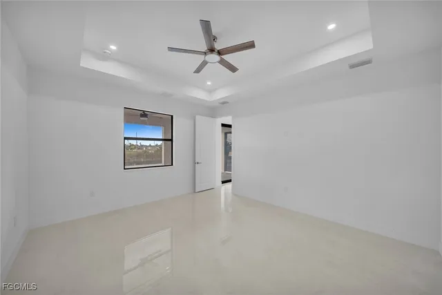 an empty room with ceiling fan and windows