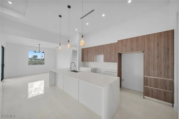 a large white kitchen with a sink a counter space and a window