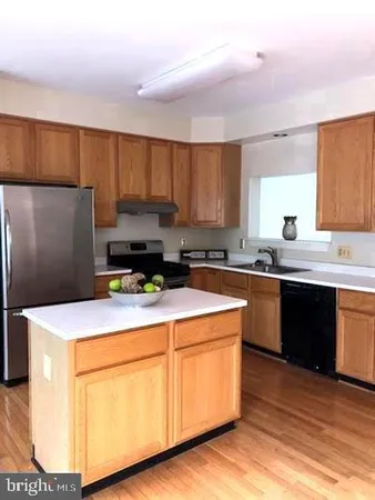 a kitchen with stainless steel appliances granite countertop a sink a stove a refrigerator a center island and cabinets