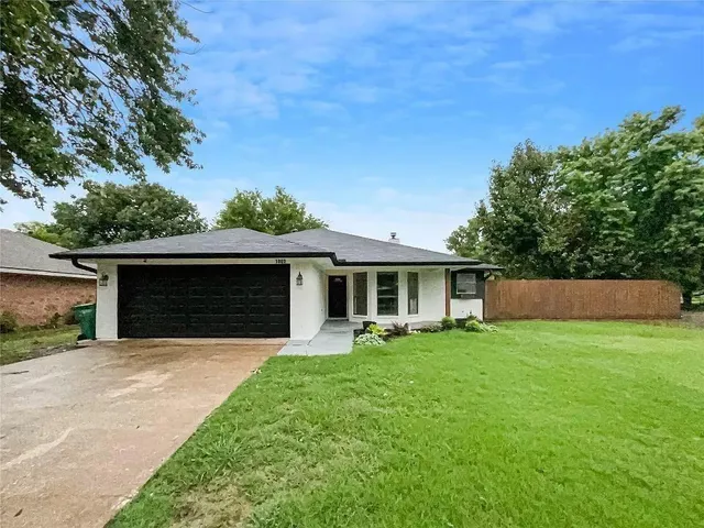a front view of house with yard and trees in the background