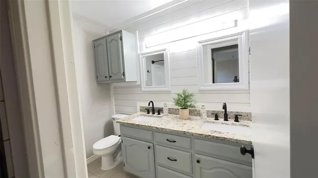 a bathroom with a granite countertop toilet sink and mirror
