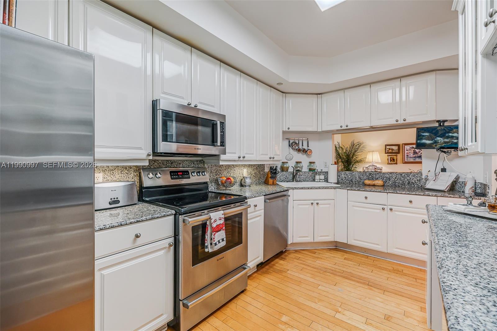 888 Brickell Key Drive, Unit 807 Miami, FL 33131 - Photo 22 of 62 a kitchen with granite countertop a stove top oven a sink dishwasher and white cabinets with wooden floor