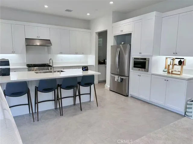a kitchen with stainless steel appliances a refrigerator sink and white cabinets