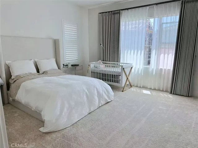 a bed sitting in a spacious bedroom next to a window
