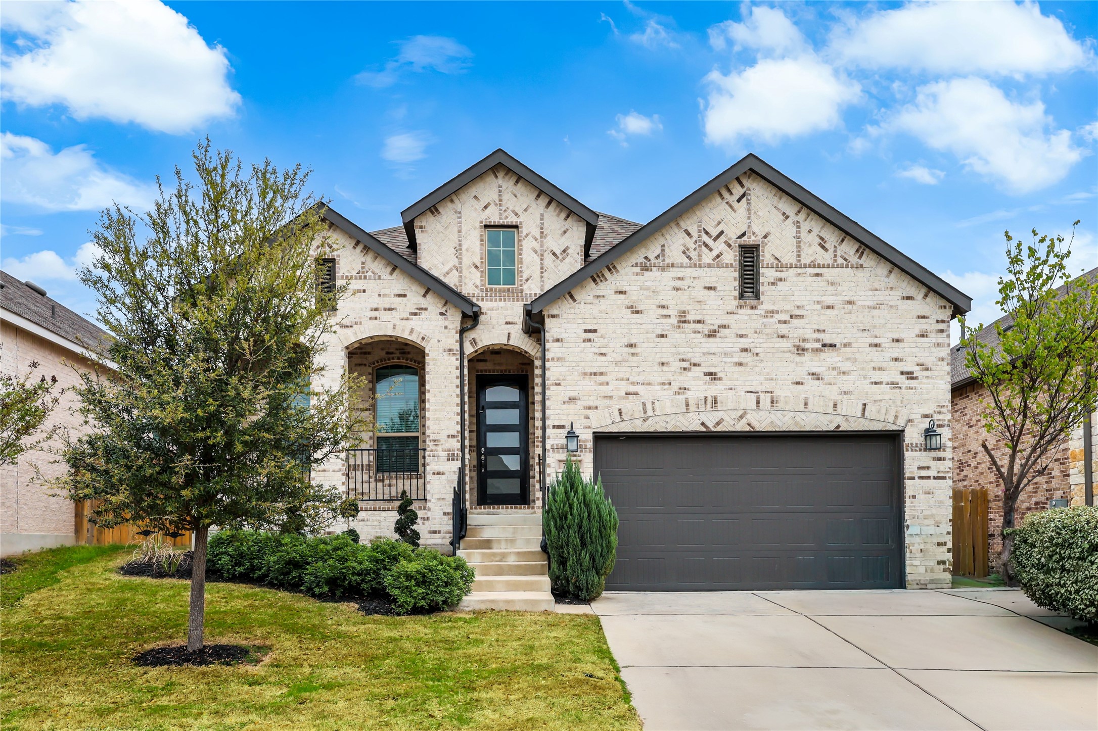 7705 Pace Ravine Drive Lago Vista, TX 78645 - Photo 1 of 40 French country inspired facade featuring brick siding, driveway, a front yard, and an attached garage