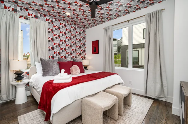 a bedroom with a bed and a large window with wooden floor