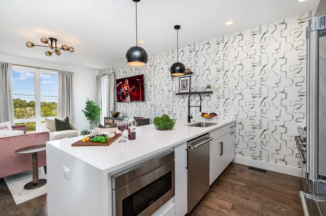 a kitchen with stainless steel appliances a sink a stove a chimney a refrigerator dining table and chairs with wooden floor