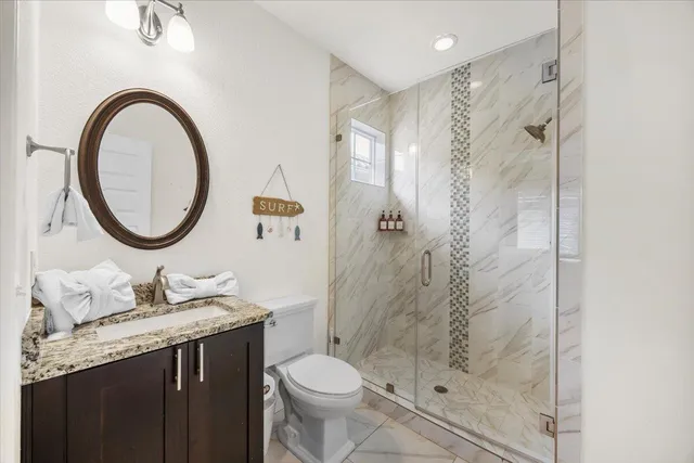 a bathroom with a granite countertop sink a toilet and a shower