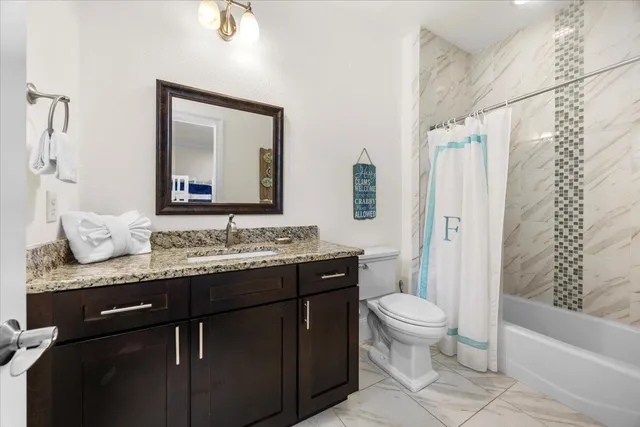 a bathroom with a granite countertop sink a toilet and a bathtub