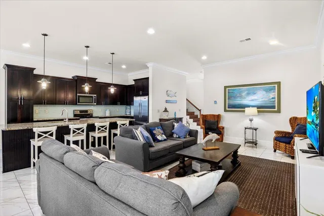 a living room with furniture kitchen view and a wooden floor