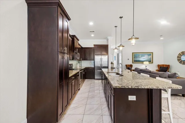 a kitchen with kitchen island granite countertop a sink a counter top space and stainless steel appliances