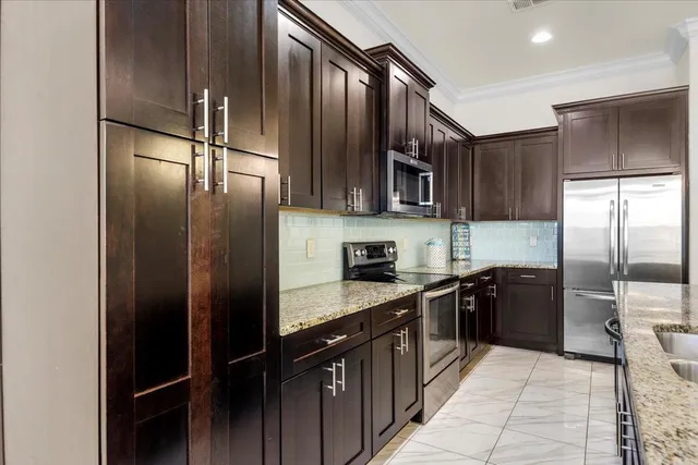 a kitchen with stainless steel appliances granite countertop a refrigerator a sink and wooden cabinets