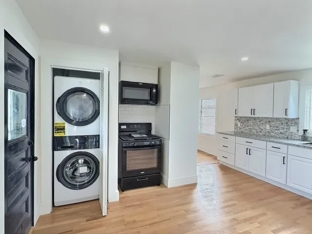 a hall with kitchen island granite countertop a wooden floor and a stove top oven