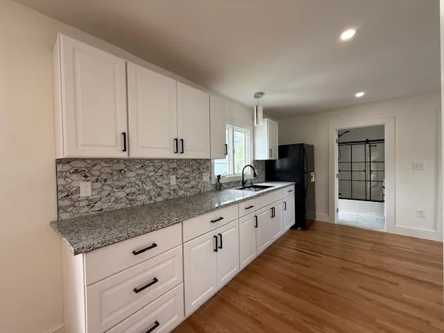 a large kitchen with granite countertop a large counter top space a sink and stainless steel appliances