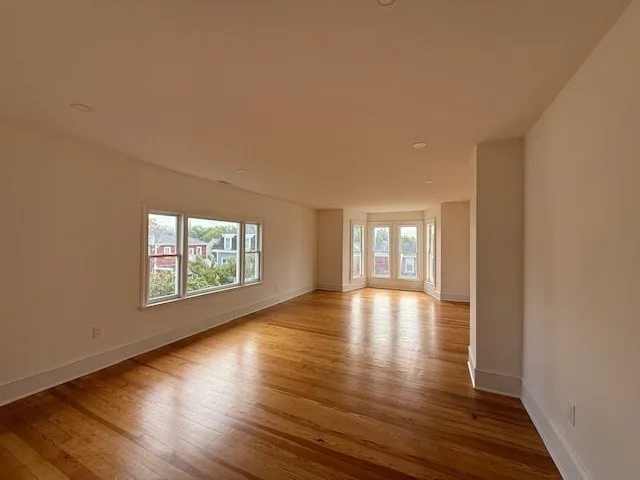 a view of an empty room with wooden floor and window