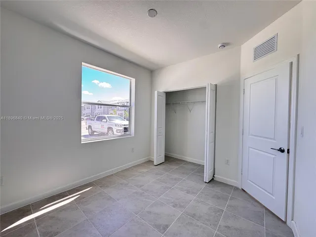 a view of an empty room with window and closet area