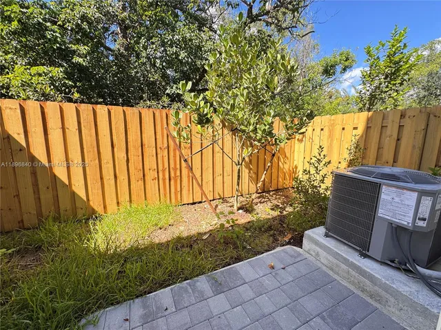a view of a backyard with potted plants and large tree