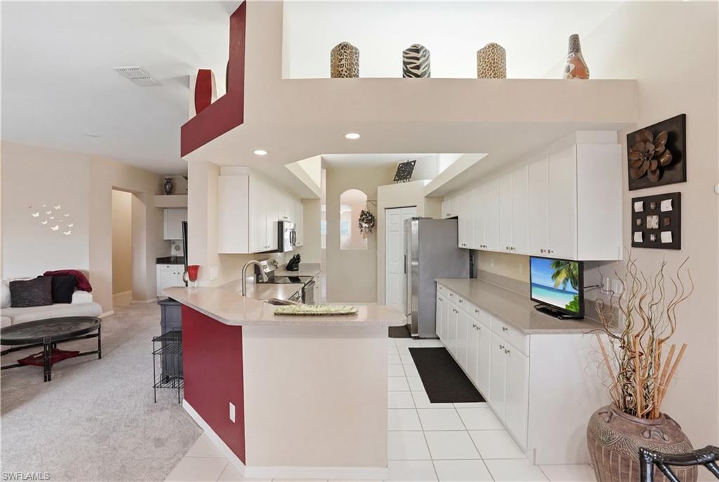 10871 Crooked River Road, Unit 202 Estero, FL 34135 - Photo 13 of 46 a kitchen with stainless steel appliances kitchen island granite countertop a sink and cabinets