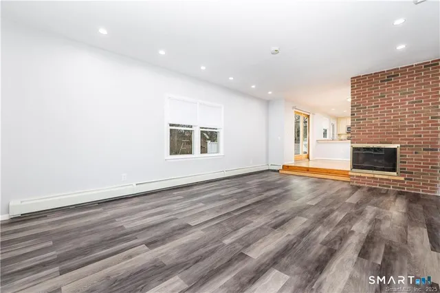 a view of empty room with wooden floor and fireplace