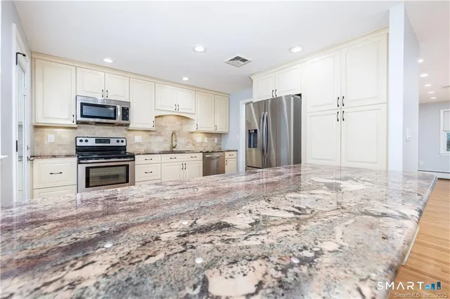 a kitchen with stainless steel appliances granite countertop a refrigerator and a stove top oven
