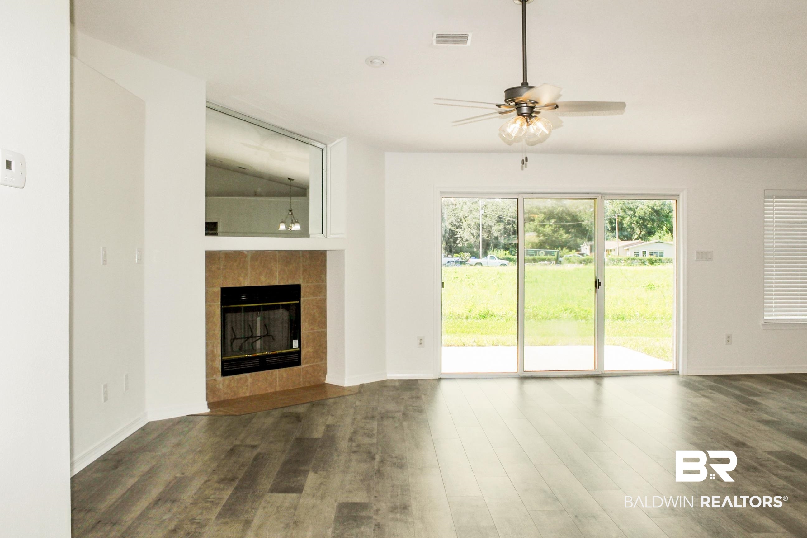 14750 Pawnee Court Foley, AL 36535 - Photo 12 of 34 Unfurnished living room featuring wood finished floors, ceiling fan, a tiled fireplace, and vaulted ceiling