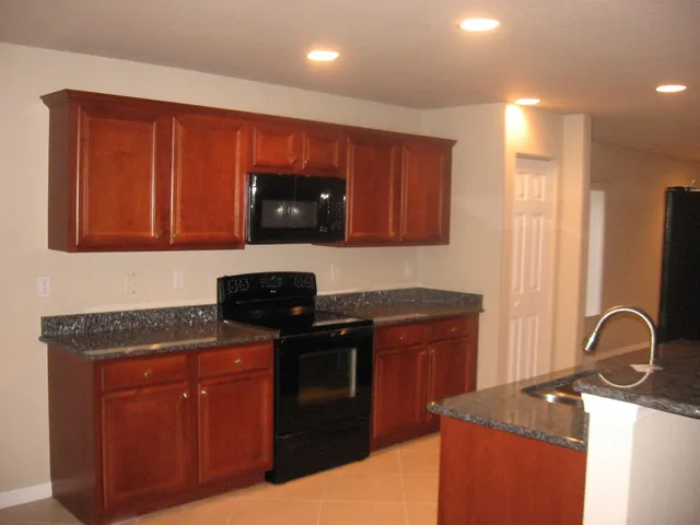 a kitchen with granite countertop stainless steel appliances wooden cabinets and a sink