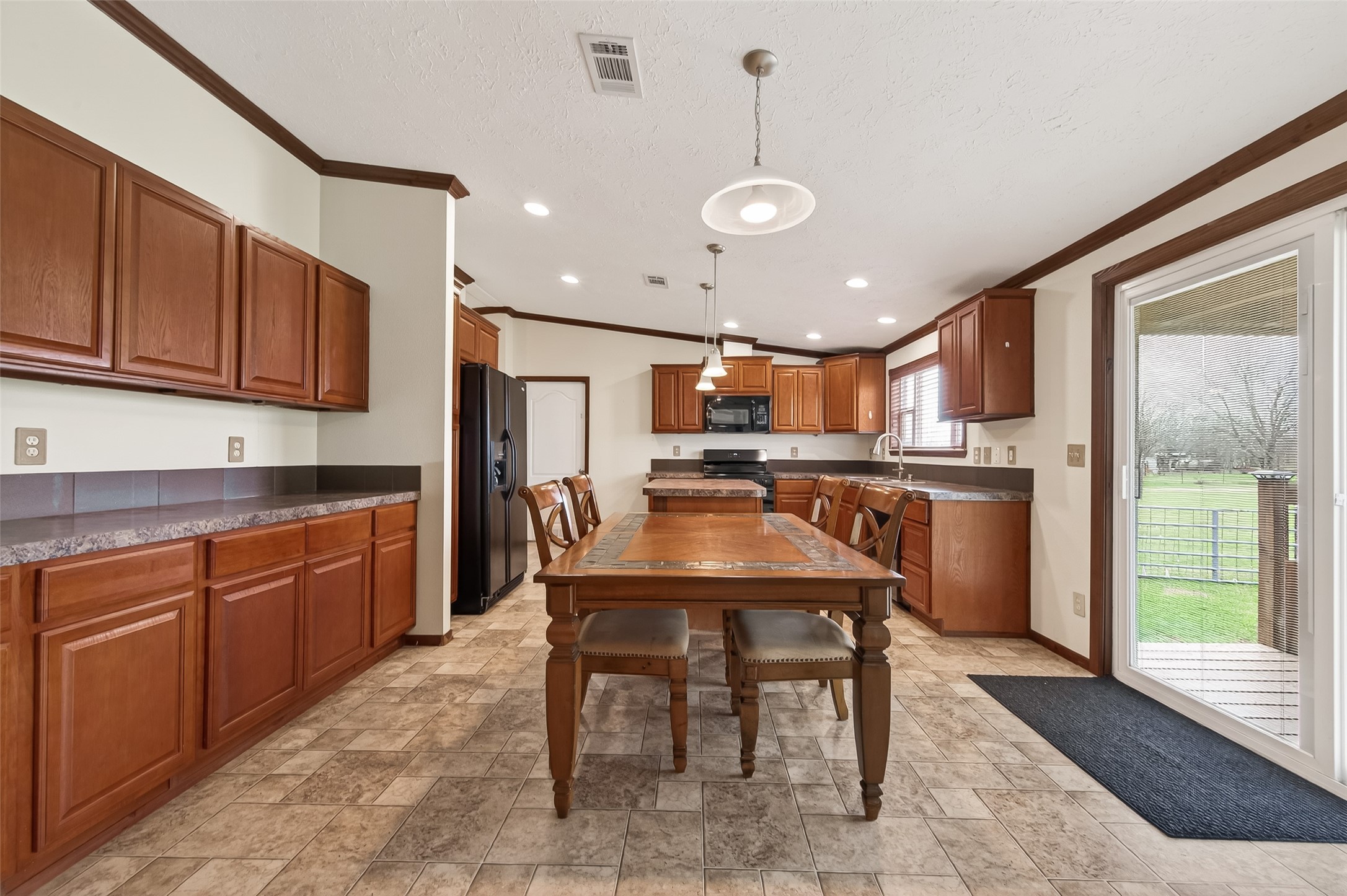 9820 Oberrender Road Needville, TX 77461 - Photo 13 of 30 a kitchen with kitchen island granite countertop a sink and a refrigerator