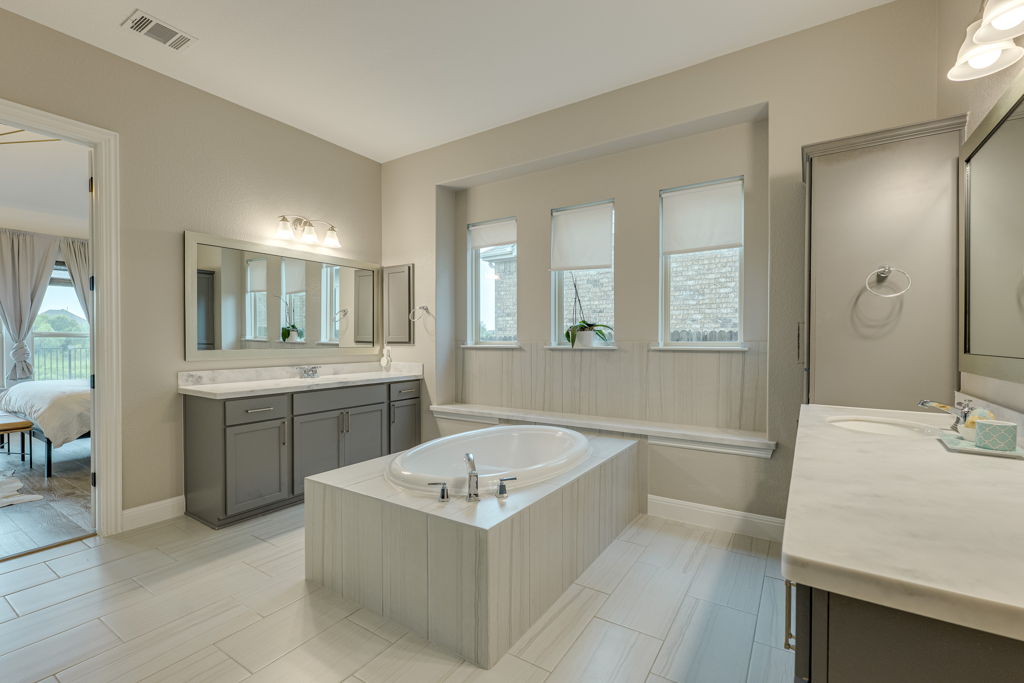 4209 Brean Down Road Pflugerville, TX 78660 - Photo 16 of 31 Marble countertops complement a large soaking tub, creating a luxurious primary bathroom.