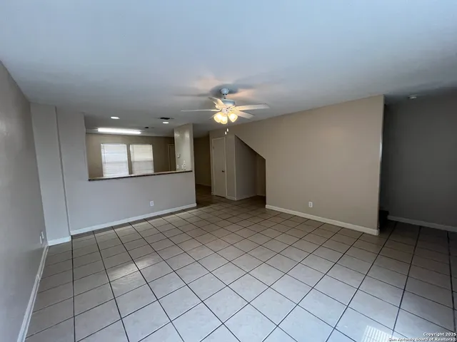 a view of an empty room with a chandelier fan and fire place