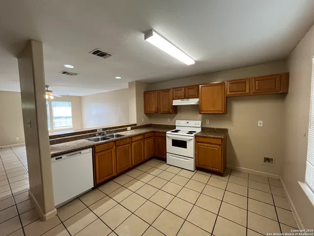a large kitchen with granite countertop a stove top oven microwave and cabinets