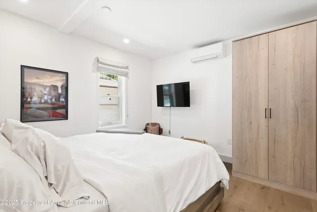 a bedroom with a large bed and a flat tv screen on dresser