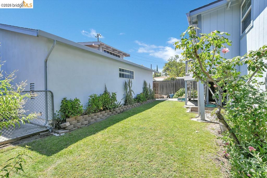 325 South 2nd Street Rio Vista, CA 94571 - Photo 24 of 33 Expansive green lawn with mature landscaping, a chain-link gate, and a retaining wall