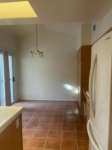 a view of a refrigerator in kitchen and an empty room
