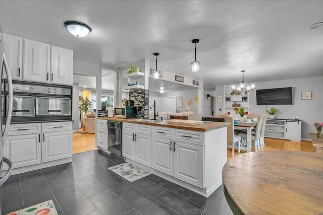 a large white kitchen with lots of counter top space and stainless steel appliances