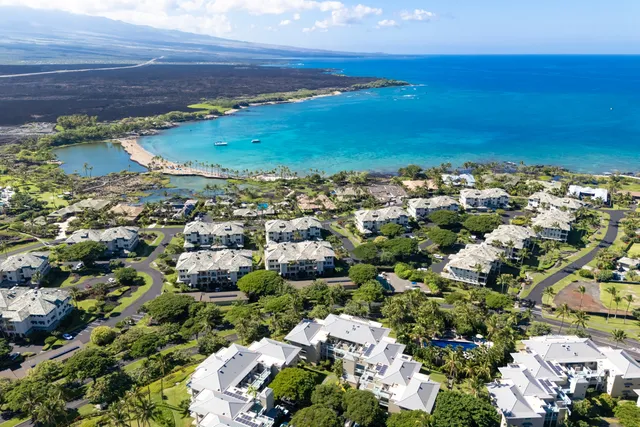 an aerial view of ocean and residential houses with outdoor space