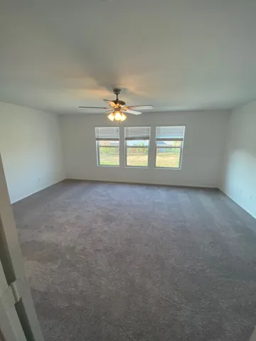 an empty room with windows and chandelier fan