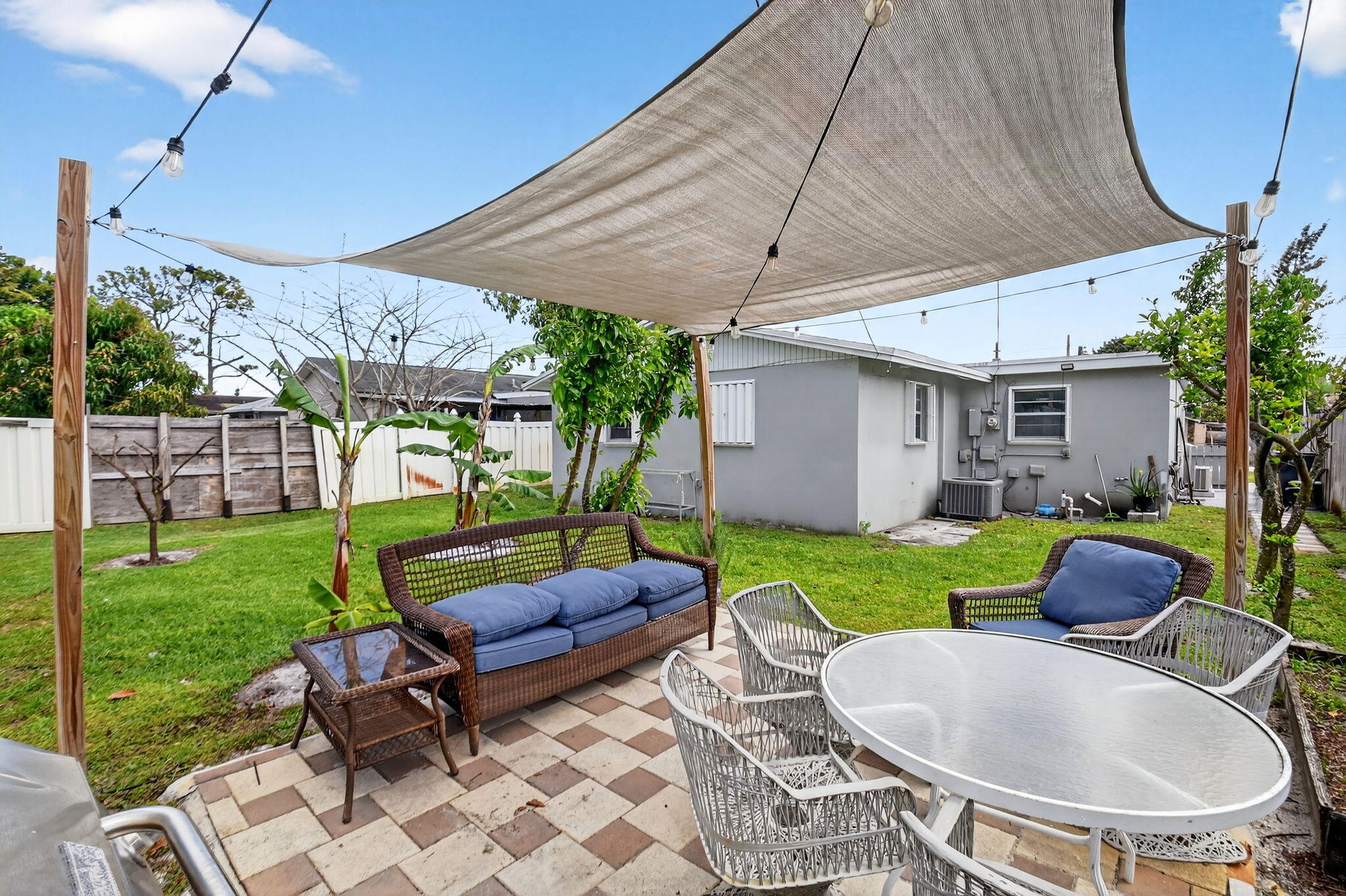 5721 Coconut Road West Palm Beach, FL 33413 - Photo 32 of 41 a backyard of a house with table and chairs potted plants and a palm tree
