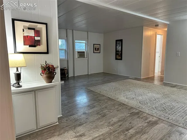 a living room with stainless steel appliances kitchen island granite countertop a sink and wooden floors