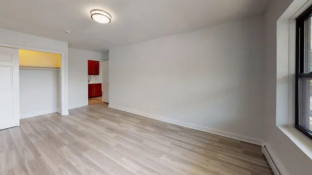 a view of empty room with wooden floor and fan