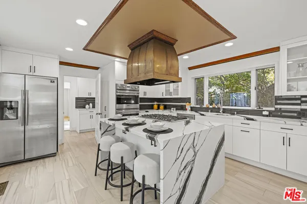 a kitchen with stainless steel appliances granite countertop a stove a refrigerator a kitchen island a stove and a refrigerator